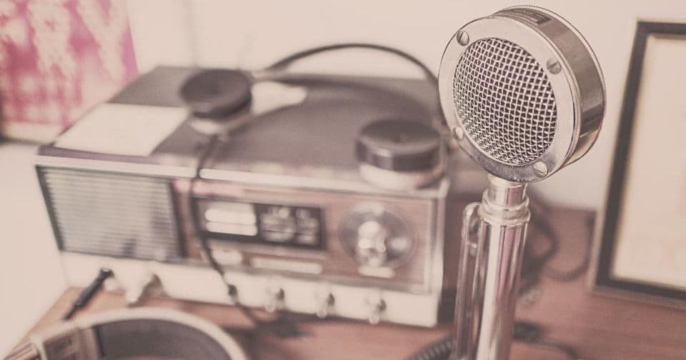 Vintage desk microphone next to a radio and headphones