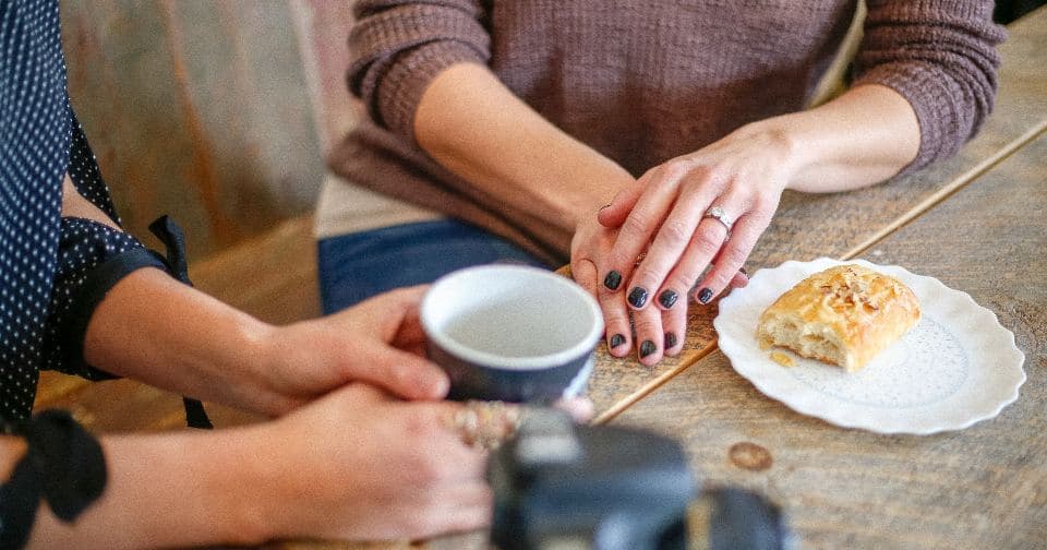 Coach and client talking over coffee at a wooden table