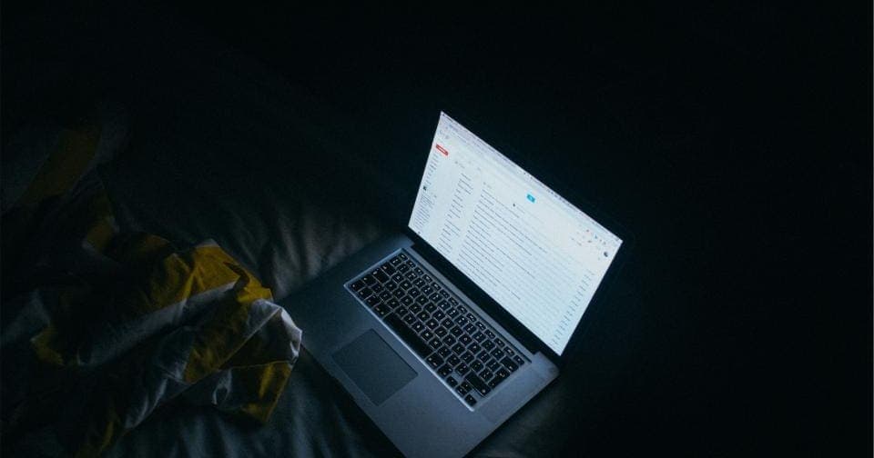 Laptop glowing at night with an email inbox open