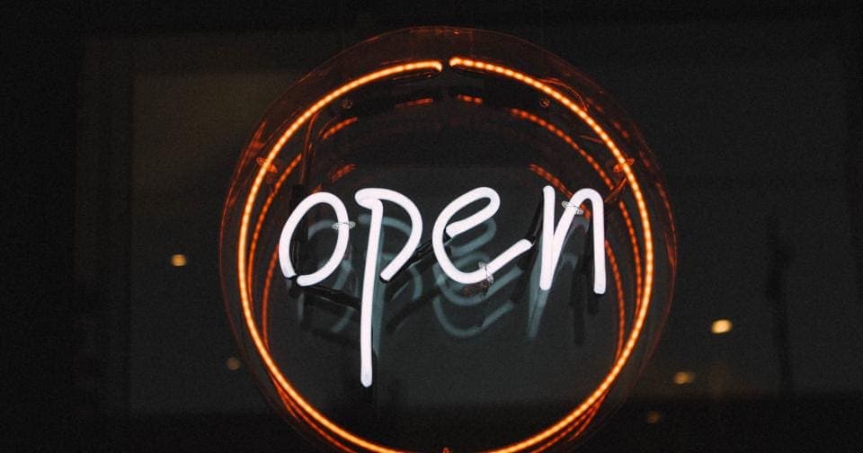 Neon open sign glowing in a shop window at night