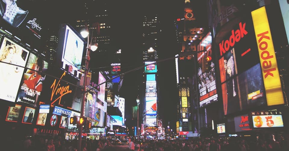 Billboards and glowing ads over a busy city square at night