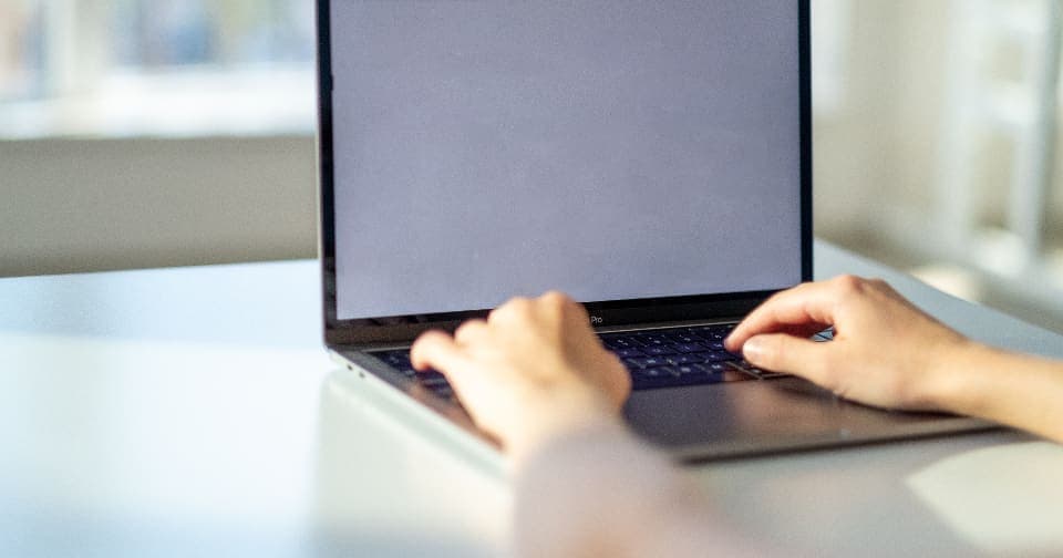 Hands typing an email on a laptop in a bright office