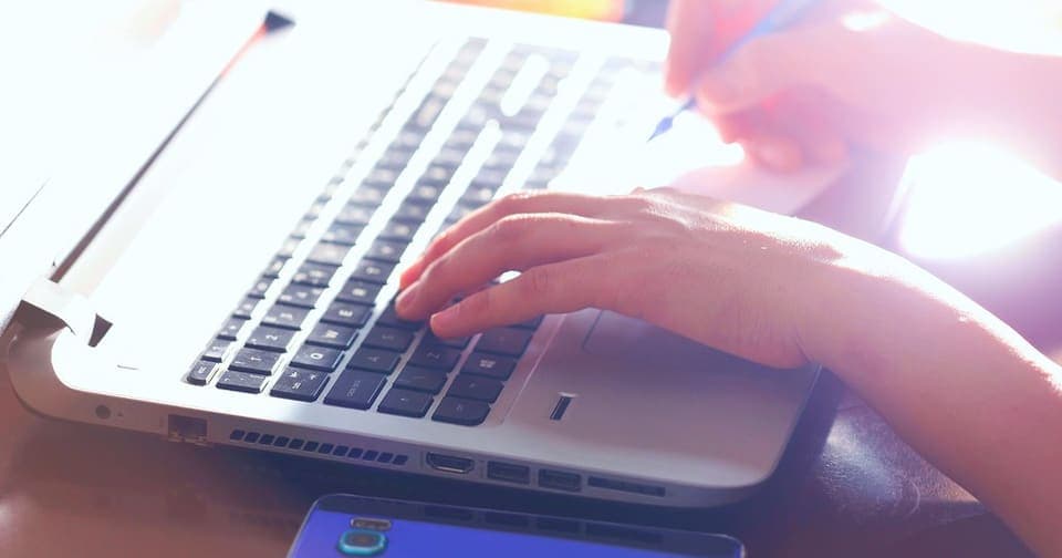 Hands typing on a laptop while planning a website
