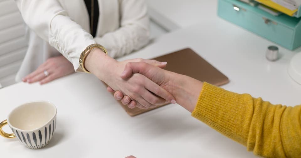 Two people shaking hands across a desk